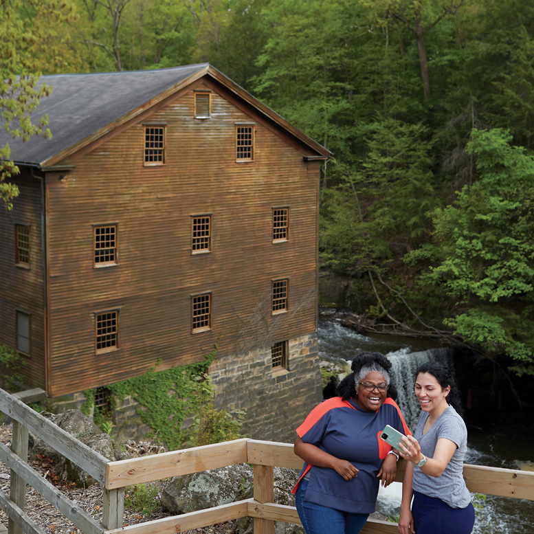Two women taking a photo in front of Lanterman’s Mill.